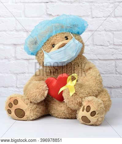 Brown Teddy Bear Holds In His Paw A Yellow Ribbon Folded In A Loop, Concept Of The Fight Against Chi
