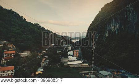 Closeup aerial cityscape at tropical forest mountain ranges. Beautiful homes, lodges, trafic roads on highland with green palm trees. Sea bay port with vessels, boats, ships at sun light