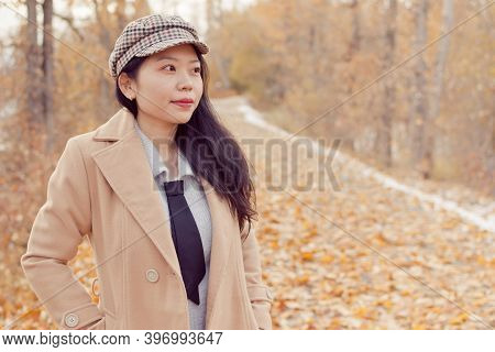 Young Asian Woman In Fall / Autumn Attire Modeling On A Hiking Trail With Fallen Leaves On The Groun