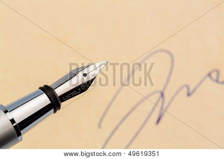 a fountain pen and a signature on yellow paper. symbolic photo for contract, and graphology testament