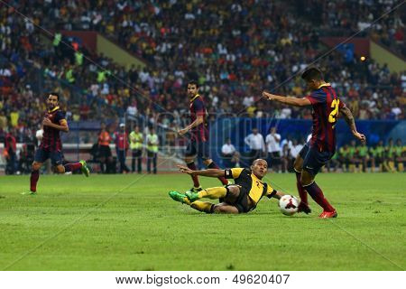 KUALA LUMPUR - AUGUST 10: Barcelona's Cristian Tello (maroon/blue) dribbles past Malaysia's Mahalli Jasuli (2) in a game at the Shah Alam Stadium on August 10, 2013 in Malaysia. Barcelona wins 3-1.