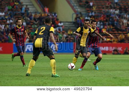 KUALA LUMPUR - AUGUST 10: Malaysia's Amri Yahya (17) defends Barcelona's Sergio Busquets (maroon/blue) attack in a game at the Shah Alam Stadium on Aug 10, 2013 in Malaysia. FC Barcelona wins 3-1.