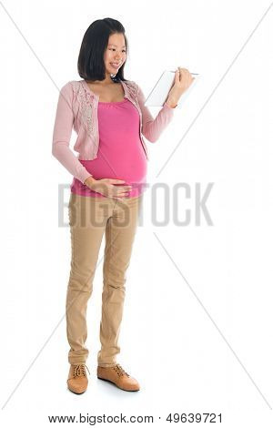 Full body six months pregnant Asian woman using digital computer tablet pc standing isolated on white background.