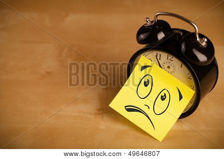 Drawn smiley face on a post-it note sticked on alarm clock