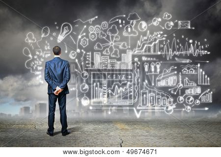 Back view image of young businessman standing against business sketch