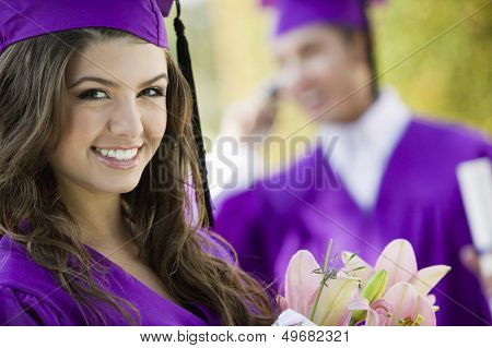 Portrait of beautiful graduate student with flower bouquet