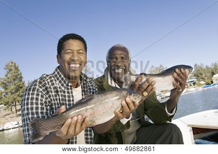 Portrait of happy father and son showing freshly caught fish
