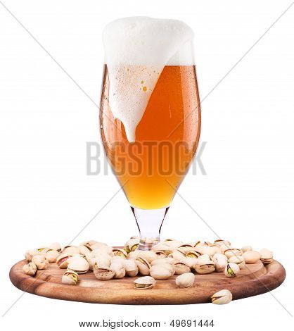 Frosty glass of light beer with pistachos
