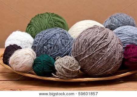Multicolored  Yarn Balls In A Straw Basket On A Wooden Table