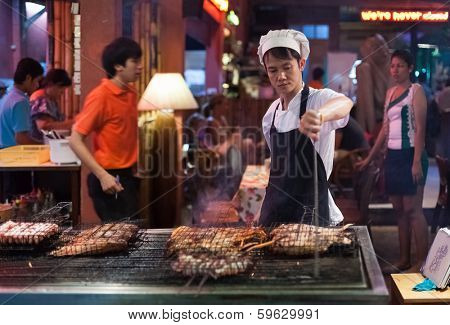 BANGKOK, THAILAND - JANUARY 9, 2012: Man prepares traditional Thai food on Khao San Road food stall. Everyday thousands of tourists and locals buys food on these stalls.