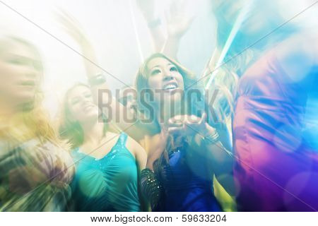 Group of party people - men and women - dancing in a disco club to the music