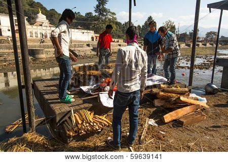 KATHMANDU, NEPAL - DEC 3, 2013: Unidentified local people during the cremation ceremony along the holy Bagmati River in Bhasmeshvar Ghat at Pashupatinath temple in Kathmandu.