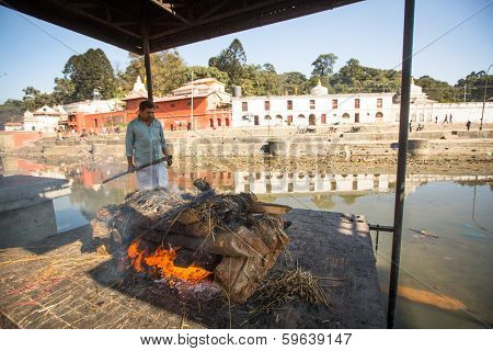 KATHMANDU, NEPAL - DEC 3, 2013: Unidentified local people during the cremation ceremony along the holy Bagmati River in Bhasmeshvar Ghat at Pashupatinath temple in Kathmandu.