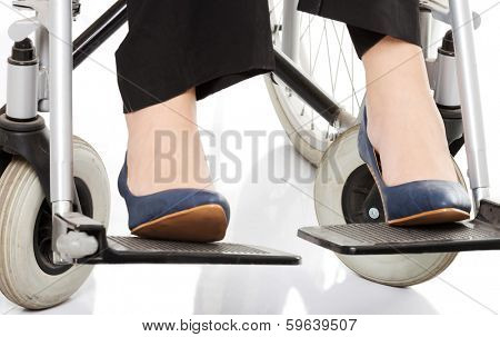 Close up on female's legs and shoues on wheelchair. Over white background.