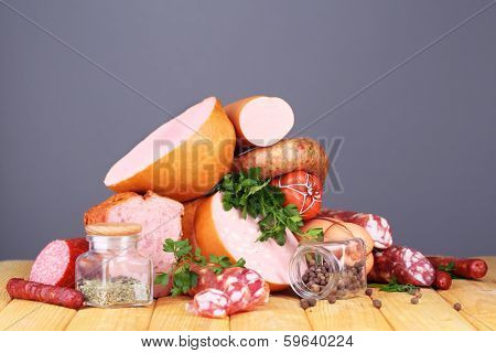 Lot of different sausages on wooden table on grey background