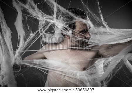 Scary network.man tangled in huge white spider web