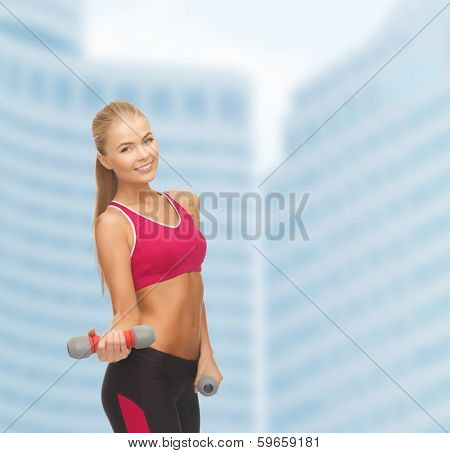 fitness and dite concept - young sporty woman with light dumbbells