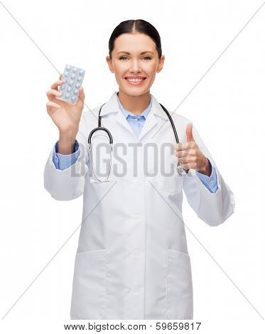 healthcare, medicine and pharmacy concept - smiling female doctor with stethoscope and pills