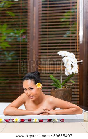 Indonesian Asian woman in wellness beauty day spa having aroma therapy bath with essential oils or salt, looking relaxed