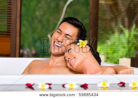 Indonesian Asian couple in wellness beauty day spa having aroma therapy bath with essential oils or salt, looking relaxed