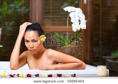 Indonesian Asian woman in wellness beauty day spa having aroma therapy bath with essential oils or salt, looking relaxed