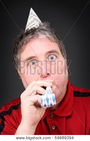 Man blowing noise maker and wearing a party hat