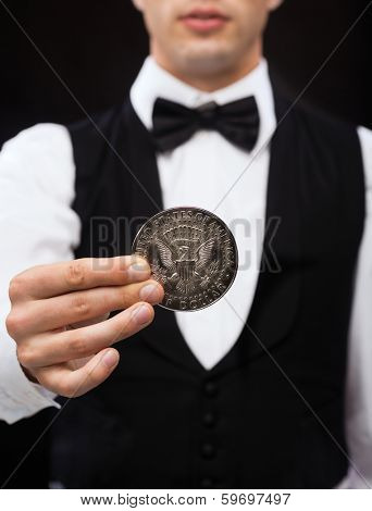 magic, performance, circus, casino and show concept - casino dealer holding half dollar coin