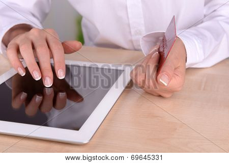 Female hands holding credit card and computer tablet on table on close up