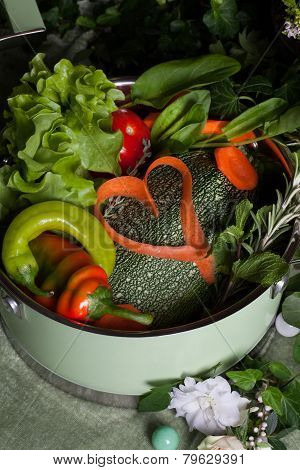 raw vegetables in a saucepan and heart carrots, vegan