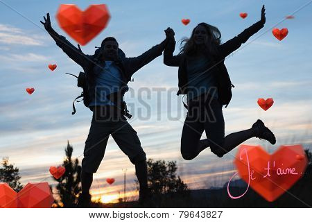 Silhouette couple jumping against the sky against valentines love hearts