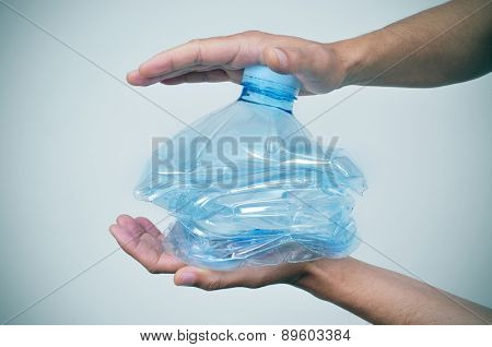 closeup of a young caucasian man smashing a plastic bottle with his hands