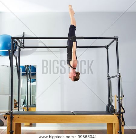 Pilates woman in cadillac acrobatic upside down balance reformer exercise at gym