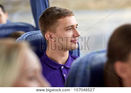 transport, tourism, road trip and people concept - happy young man sitting in travel bus and looking through window