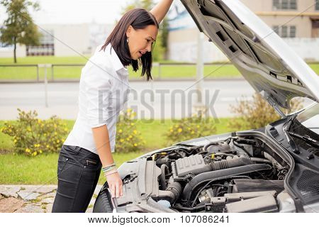 Woman looking at broken cars motor