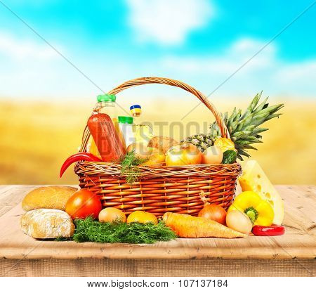 fruits and vegeetables and other food on wooden desk and autumn field on background