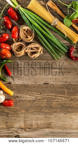 Italian food background with  raw pasta and vegetables on wooden table