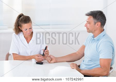 Doctor Using Lancelet On Man's Finger