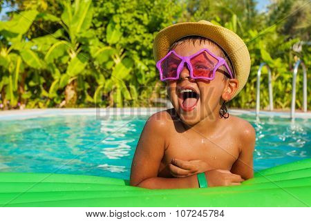 Laughing boy in star-shaped sunglasses on airbed