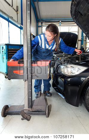 Mechanic, using an advanced measturing tool, to adjust the hight of a head light beam and high beam of a car as part of a MOT test