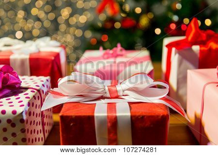 christmas, holidays, presents, new year and celebration concept - close up of gift boxes over christmas tree lights