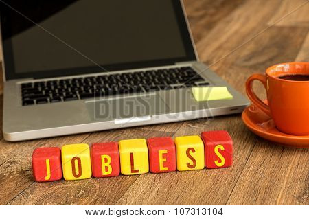 Jobless written on a wooden cube in front of a laptop