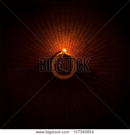 A glowing earthen ghee lamp in the dark. Handwritten mantra visible at the background.
