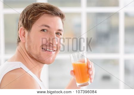 Young handsome guy enjoys a glass of juice.