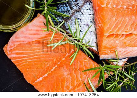 Portions Of Fresh Raw Salmon Fillets With Aromatic Herbs And Olive Oil