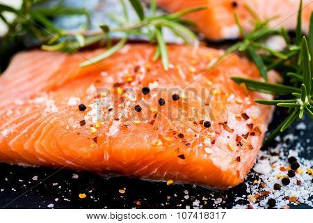 Portions Of Fresh Raw Salmon Fillets With Aromatic Herbs And Olive Oil