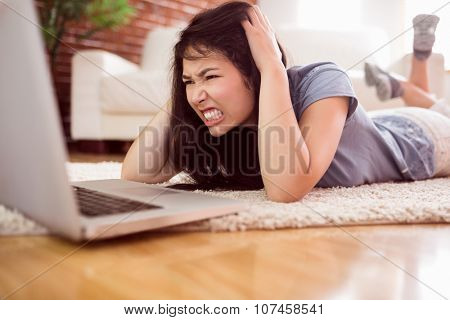 Asian angry woman using laptop on floor at home in the living room