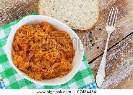 Polish bigos in white bowl on rustic wooden surface