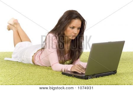 Giovane donna con il computer portatile sul tappeto verde