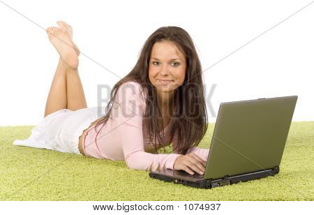Giovane donna con il computer portatile sul tappeto verde