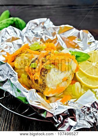 Pike with carrots in foil on dark board